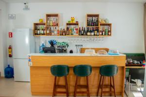 a kitchen with a counter with four green bar stools at Lily holiday hotel in Mindelo