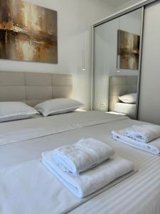Una cama blanca con dos toallas blancas encima. en Apartman Noa, en Međugorje