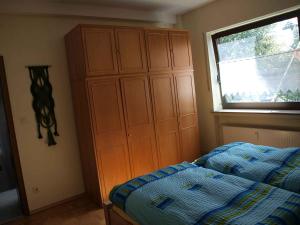 1 dormitorio con 1 cama y un gran armario de madera en Ferienwohnung Boueke, en Herscheid