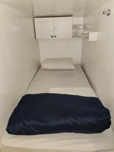 a bed in a small room with a blue blanket on it at Vila Rock Hostel - próximo Allianz Parque, Vila Madalena, Av Paulista, Hospital das Clínicas INCOR FMUSP in São Paulo