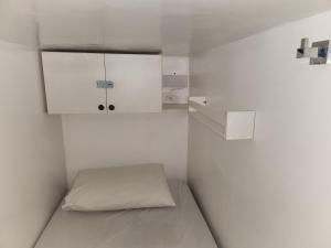 a small white room with a bed and cabinets at Vila Rock Hostel - próximo Allianz Parque, Vila Madalena, Av Paulista, Hospital das Clínicas INCOR FMUSP in São Paulo