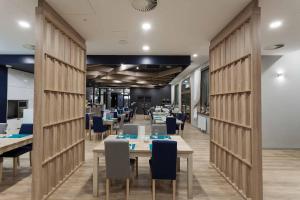a dining room with tables and blue chairs at Hotel Zatoka in Gdańsk