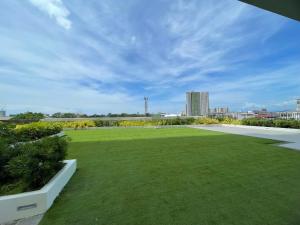 a large yard with green grass and buildings in the background at Peaceful and Convenient Condo - Avida Tower in Cagayan de Oro
