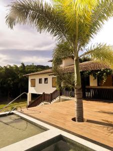 ein Haus mit einer Palme und einem Pool in der Unterkunft Fazenda do Barro CMD Maravilhosa Casa de Fazenda in Conceição do Mato Dentro