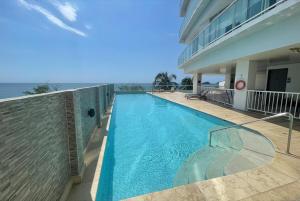 a swimming pool in front of a building with the ocean at Ocean View Penthouse in Gaira
