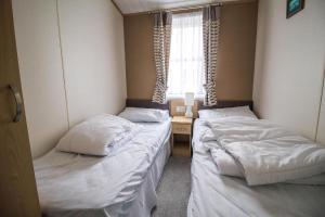 two beds in a room with a desk and a window at Beautiful Lodge At Manor Park Nearby Hunstanton Beach Ref 23021C in Hunstanton +13 photos
