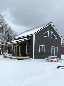 una casa nera con un portico nella neve di Sugar House Cottage close to Smugglers Notch a Cambridge