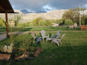 three chairs and a table in a field with mountains at Rincón Bonito in El Hoyo +50 photos