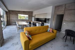 a living room with a yellow couch and a kitchen at Sweetstaybykw Moderna Casa Campo con Piscina in Asprillas