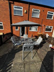 a table and chairs with an umbrella in front of a brick building at Liberty Guest House in Liverpool
