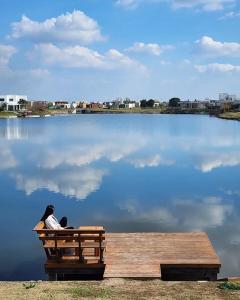 a person sitting on a bench in front of a lake at Casa Familiar Vista al Lago - Barrio Privado Escobar - 3 habitaciones - Pileta Climatizada y Jacuzzi - Parrilla - 364HOUSE in Zelaya