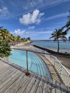 a swimming pool next to a beach with palm trees at Charmant T2 avec terrasse - Résidence Manganao in Saint-François