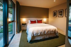 a bedroom with a large bed with red pillows at Rangers Retreat - Mountain Views - Rural in Lake Hawea