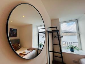 espejo redondo en una habitación con cama y litera en Bramble Apartment, en Fort William