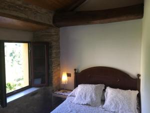 a bedroom with a bed with white sheets and a window at La Cabaña del Abuelo en la aldea cerca del mar in Santa Marta de Ortigueira
