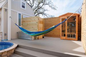 a hammock on a deck with a fence at Secluded Luxury Couples cabin Sauna Pool in Wimberley