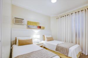 two beds in a white room with a window at Roomo Transamerica SP Itaim Bibi in Sao Paulo