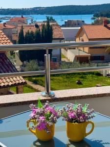 two cups of flowers on a glass table with a view at Apartments Terra Solaris in Medulin