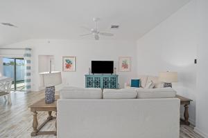 a white living room with a white couch and a tv at Free Golf Cart & Netflix Included - 2 Mins to Brownwood Paddock-Sleeps 6 in The Villages
