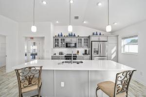 a white kitchen with a large white counter and chairs at Free Golf Cart & Netflix Included - 2 Mins to Brownwood Paddock-Sleeps 6 in The Villages