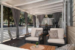 ビオグラード・ナ・モルにあるAZURA Mobile Home, Biograd na Moruの椅子2脚とテーブル付きのスクリーンポーチ