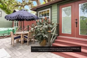 un portico di una casa con tavolo e ombrellone di Mills Cottage a Orlando Altre 13 foto