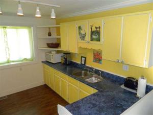 a kitchen with yellow cabinets and a sink at Cute and Cozy Lakefront Cottage in Wellington