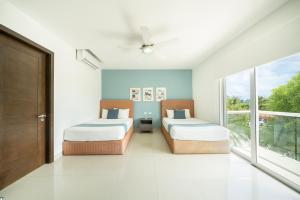 deux lits dans une chambre avec deux fenêtres dans l'établissement Luxury 2 BR Condo with tub & Infinity Pool - Beach Side At Mareazul - Sirenita G, à Playa del Carmen