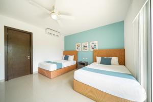 une chambre avec deux lits et une fenêtre dans l'établissement Luxury 2 BR Condo with tub & Infinity Pool - Beach Side At Mareazul - Sirenita G, à Playa del Carmen 20 autres photos