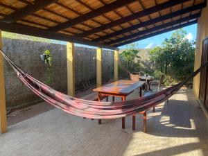 a hammock on a patio with a table and chairs at Casa do Sol in Tibau do Sul