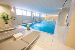 a large swimming pool in a room with chairs at Hotel TTS**** Spa&Wellness Covasna in Covasna