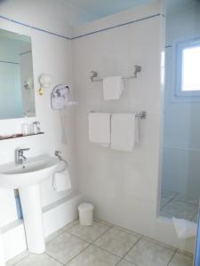 a white bathroom with a sink and a shower at Hôtel de L'Avenue in Saintes