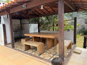 a wooden picnic table and benches under a pavilion at Sitio descanso da Serra in Jaboticatubas