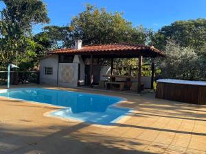 a pool with a gazebo and a picnic table at Sitio descanso da Serra in Jaboticatubas