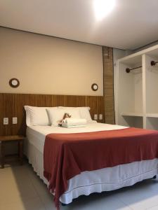 a bedroom with a large bed with a red blanket at Loft Vila Murici in Flecheiras