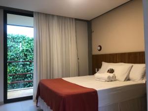 a bedroom with a bed and a large window at Loft Vila Murici in Flecheiras