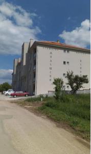 a large white building on the side of a road at Apartman Una in Soko Banja