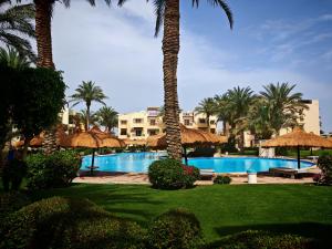 a resort with a swimming pool with palm trees and umbrellas at Luxury Poolside Retreat Elegant Apartment two rooms within a Seafront Hotel in Sharm El Sheikh