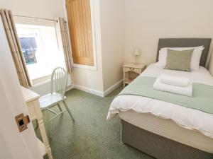 ein Schlafzimmer mit einem Bett, einem Stuhl und einem Fenster in der Unterkunft 1 Brookside in Warcop