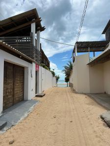 a dirt road between two buildings with the ocean in the background at Pousada Brisa do Mar in Galinhos +8 photos