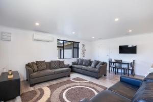 a living room with two couches and a table at Coastal Comfort - Foxton Beach Holiday Home in Foxton