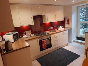 a kitchen with white cabinets and a stove top oven at The Garden Flat in Windermere