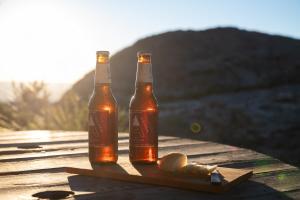 two bottles of beer sitting on a wooden table at Rustic Mountain Shelter Pure Nature in Las Rabonas +57 photos