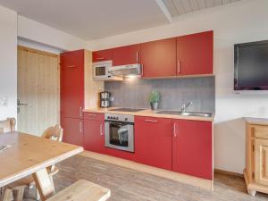 a kitchen with red cabinets and a wooden table at Bergjuwel Typ 5 in Fügen