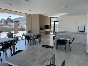 a dining room with tables and chairs and a kitchen at Depto Paseo Quattro in Villa Carlos Paz