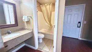 a bathroom with a sink and a toilet and a door at Valley Inn in Watsonville