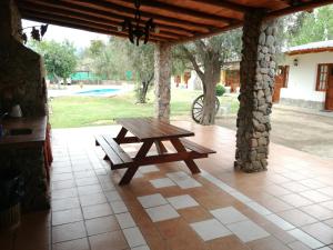 a wooden picnic table on a patio with a stone wall at Posada Chilecito in San Miguel