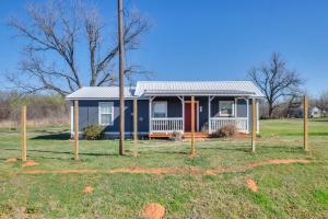 una casa blu con un portico in un campo di Pet-Friendly Home with Porch Near Chickasha! a Ninnekah