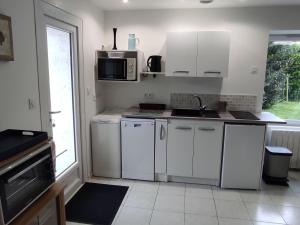 a white kitchen with a sink and a microwave at Fermette Rénovée avec Jardin Privatif et Wifi à 12km des Plages - FR-1-306-1257 in Bourgneuf-en-Retz