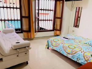 a bed and a chair in a room with windows at Hotel casa gustadora in Cali